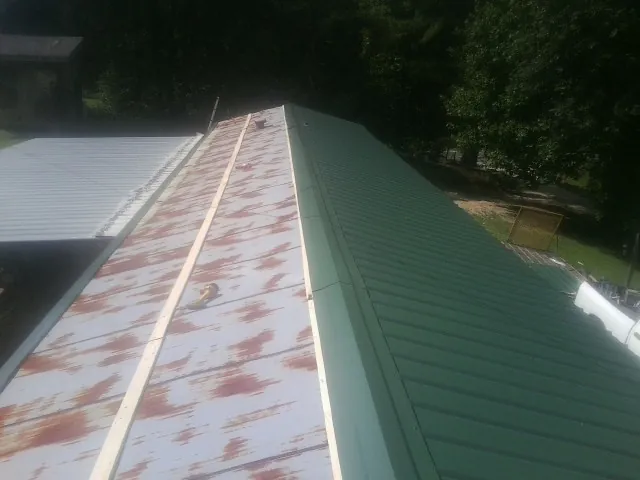 Old rusted panels beside newly installed green metal roofing — Wind Damage Roof Repair by Roofing Brothers in Beresford